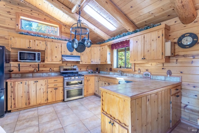 kitchen with wood walls, stainless steel appliances, beamed ceiling, wooden ceiling, and light brown cabinets