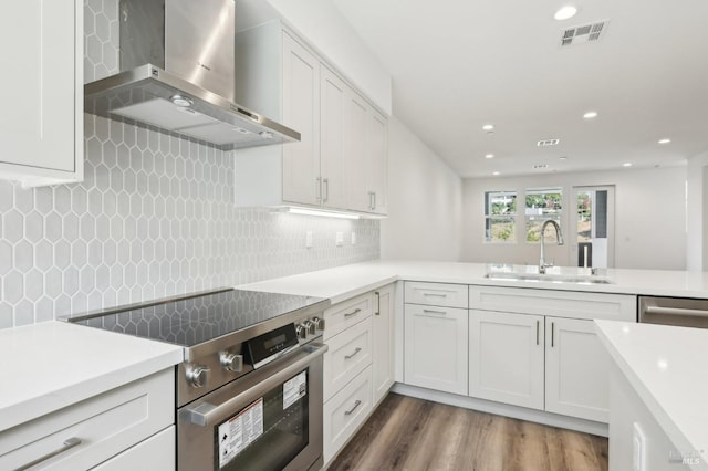 kitchen with visible vents, wall chimney exhaust hood, appliances with stainless steel finishes, light countertops, and a sink