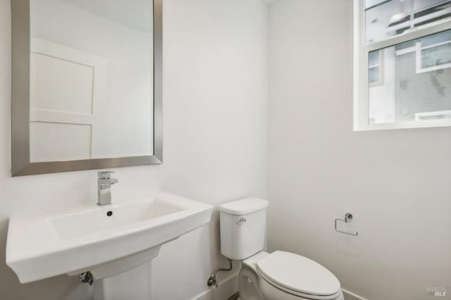 bathroom featuring toilet, baseboards, and a sink