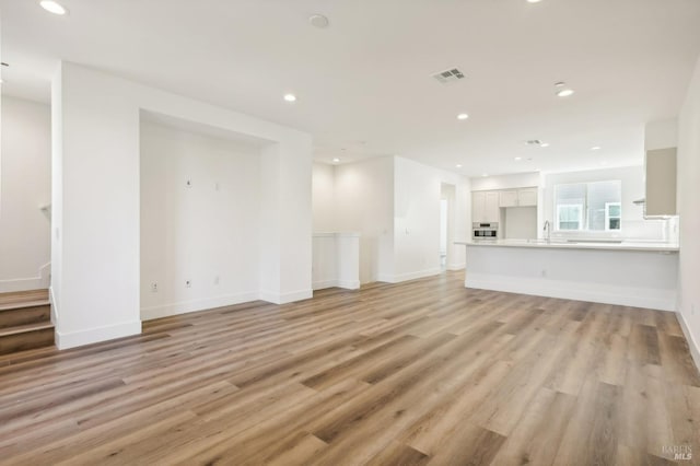 unfurnished living room featuring recessed lighting, visible vents, light wood-style flooring, and baseboards