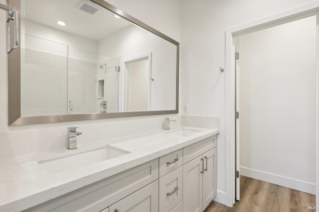 bathroom featuring a stall shower, visible vents, a sink, and wood finished floors