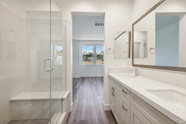 bathroom with hardwood / wood-style floors, a shower with door, and vanity