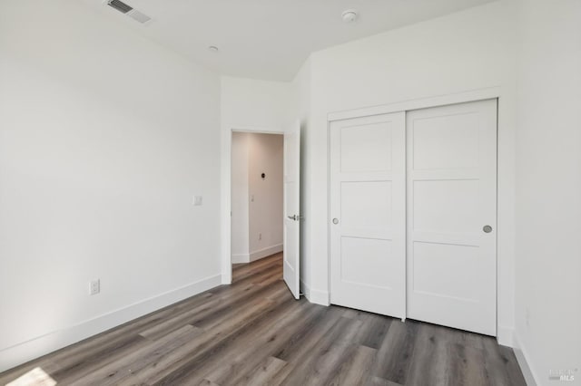 unfurnished bedroom with dark hardwood / wood-style floors and a closet