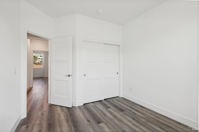 unfurnished bedroom featuring dark hardwood / wood-style flooring and a closet