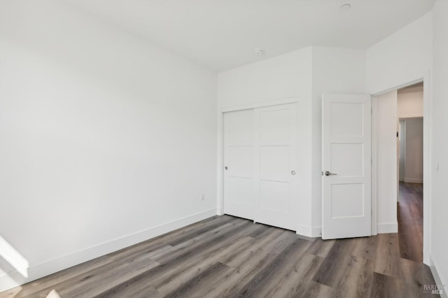 unfurnished bedroom featuring dark hardwood / wood-style flooring and a closet