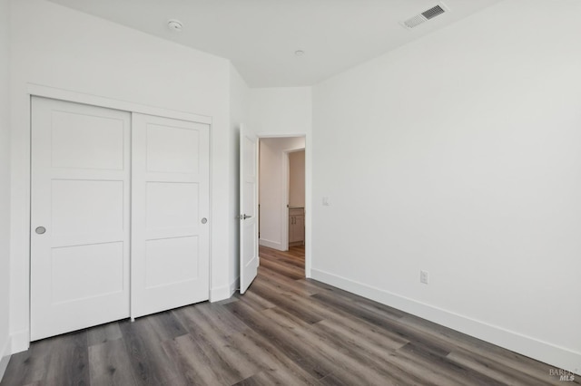 unfurnished bedroom featuring dark hardwood / wood-style flooring and a closet