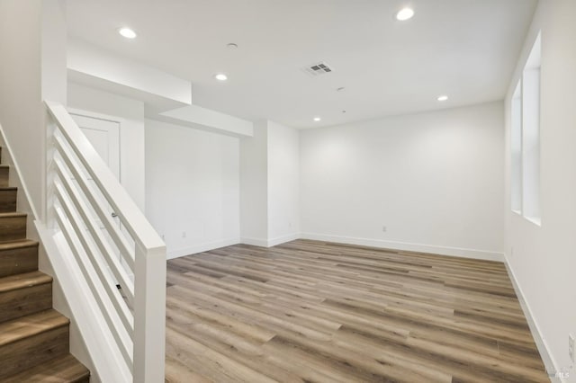 unfurnished room featuring light wood-style flooring, stairs, baseboards, and recessed lighting