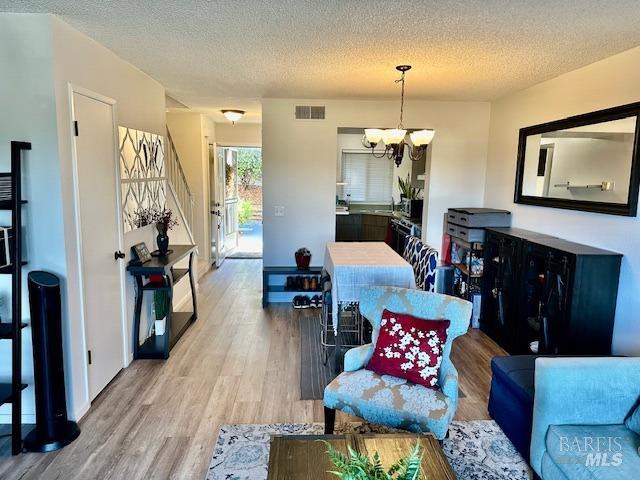 living room featuring a textured ceiling, light hardwood / wood-style flooring, and a notable chandelier