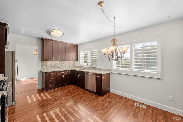 kitchen with pendant lighting, appliances with stainless steel finishes, hardwood / wood-style flooring, and sink