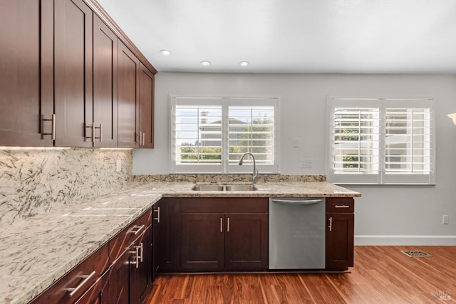 kitchen featuring stainless steel dishwasher, sink, light stone counters, and hardwood / wood-style floors