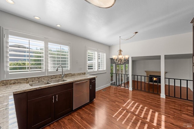 kitchen with sink, light stone counters, stainless steel dishwasher, hanging light fixtures, and dark hardwood / wood-style flooring