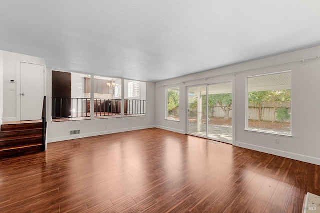 unfurnished living room with hardwood / wood-style floors and an inviting chandelier