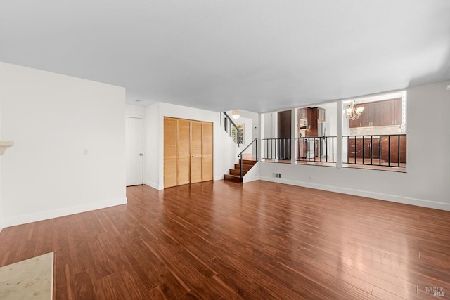 unfurnished living room featuring a notable chandelier and dark hardwood / wood-style floors