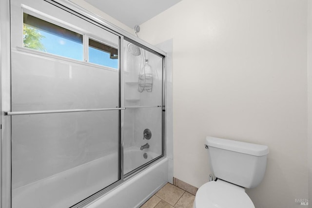 bathroom featuring bath / shower combo with glass door, tile patterned floors, and toilet