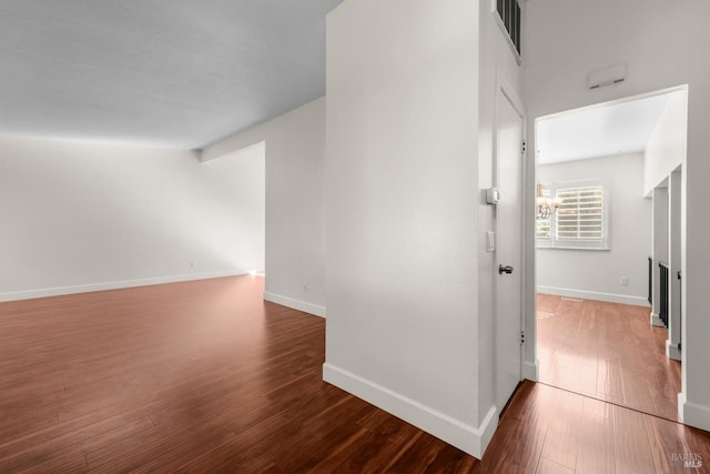 hall with hardwood / wood-style floors, vaulted ceiling, and a notable chandelier