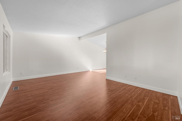 empty room featuring lofted ceiling with beams and hardwood / wood-style flooring