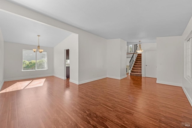 unfurnished living room featuring an inviting chandelier, wood-type flooring, and vaulted ceiling