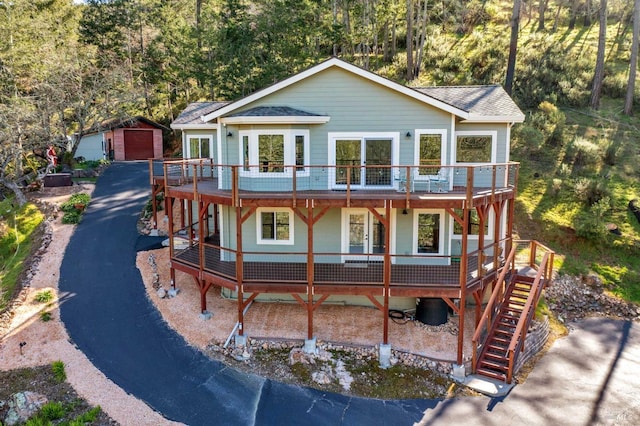 view of front of house with a garage, a shingled roof, aphalt driveway, an outbuilding, and a deck