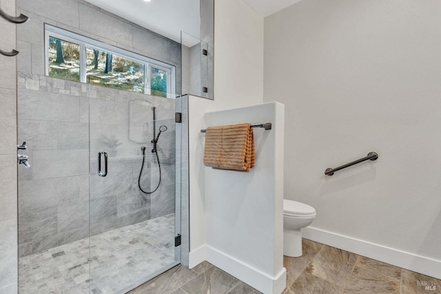 bathroom featuring toilet, a shower stall, and baseboards