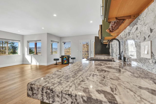 kitchen featuring recessed lighting, a sink, light wood-style flooring, and baseboards