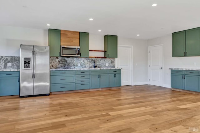 kitchen with stainless steel appliances, light wood-style floors, green cabinets, decorative backsplash, and open shelves