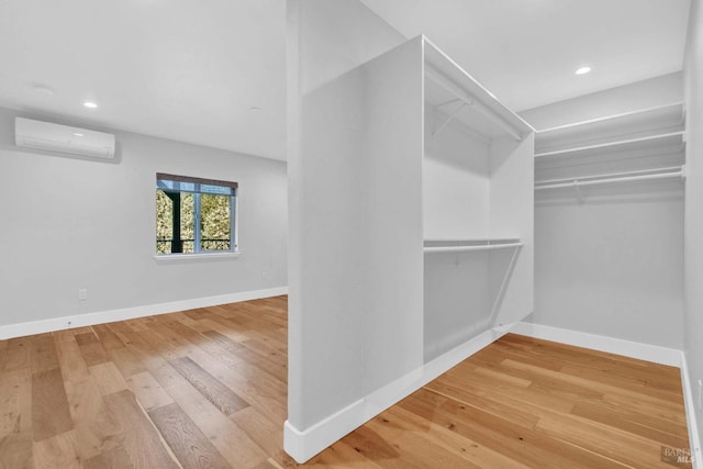 spacious closet featuring wood finished floors and a wall mounted AC