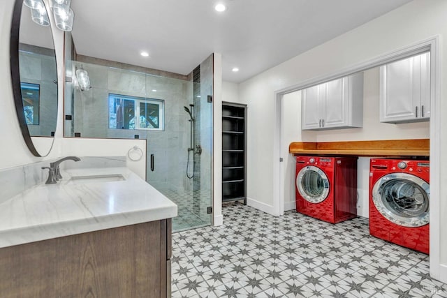 laundry room with light floors, independent washer and dryer, a sink, and cabinet space