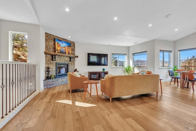 living room featuring light wood-type flooring, plenty of natural light, a fireplace, and recessed lighting