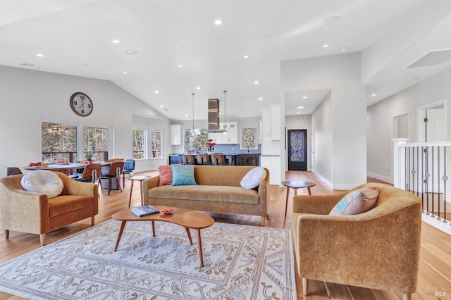 living area with recessed lighting, visible vents, light wood-style flooring, high vaulted ceiling, and baseboards