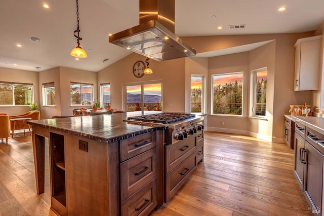 kitchen featuring island range hood, visible vents, white cabinetry, stainless steel gas stovetop, and pendant lighting