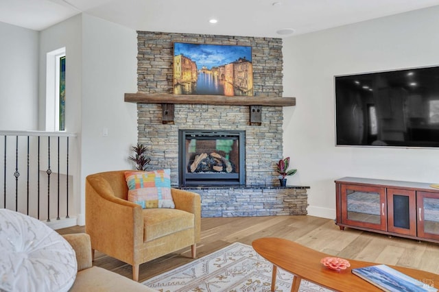 living area featuring a stone fireplace, wood finished floors, and baseboards