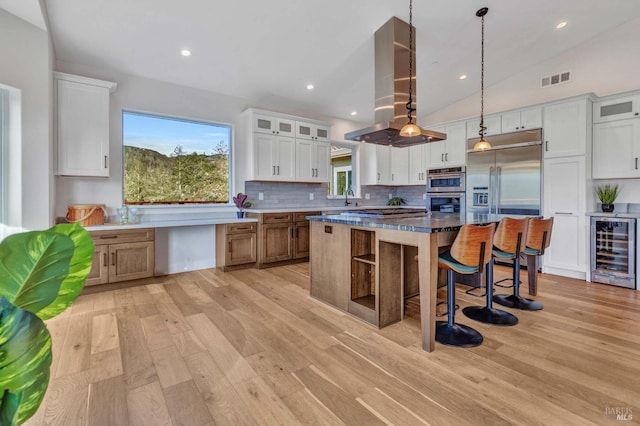 kitchen featuring wine cooler, a spacious island, glass insert cabinets, white cabinetry, and island range hood