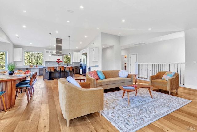 living room featuring lofted ceiling, light wood finished floors, and recessed lighting