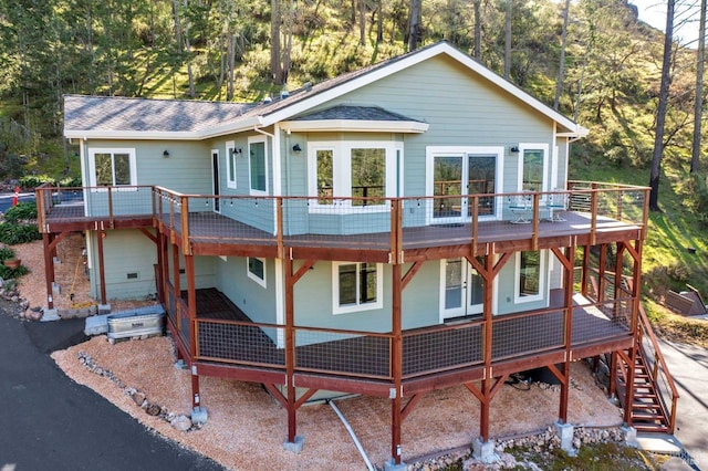 view of front of house featuring a shingled roof, stairway, and a wooden deck