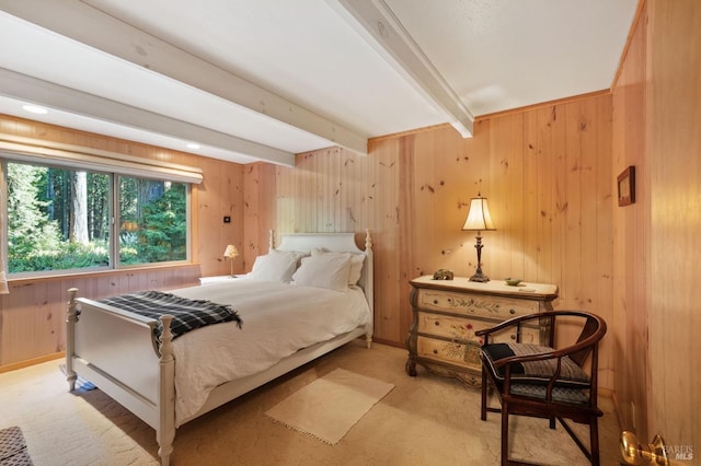 bedroom featuring light carpet, baseboards, beam ceiling, and wooden walls
