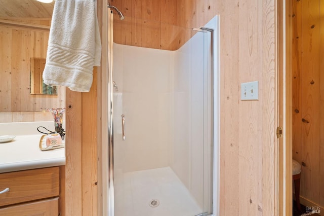 full bathroom featuring a shower stall, wooden walls, and vanity
