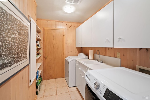 clothes washing area with cabinet space, light tile patterned floors, visible vents, washer and dryer, and wood walls