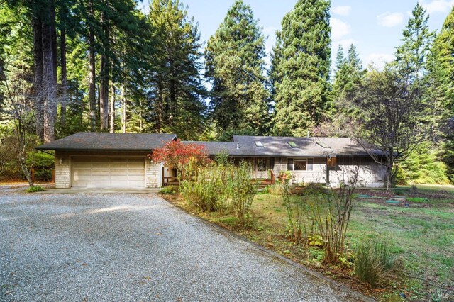 single story home with an attached garage and gravel driveway
