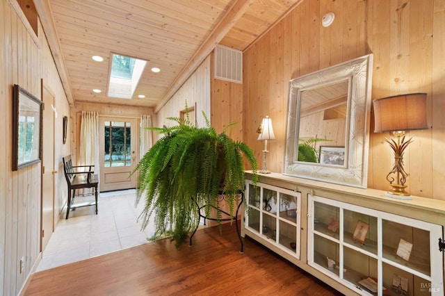 corridor featuring a skylight, visible vents, wooden ceiling, wood finished floors, and wood walls