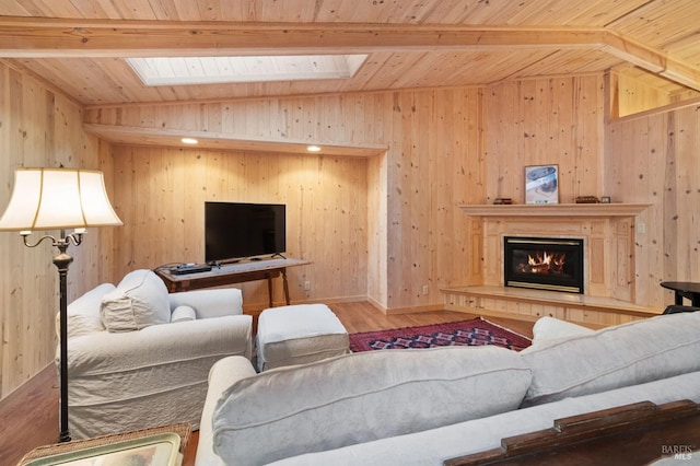 living room featuring a glass covered fireplace, wooden ceiling, vaulted ceiling with skylight, and wood finished floors