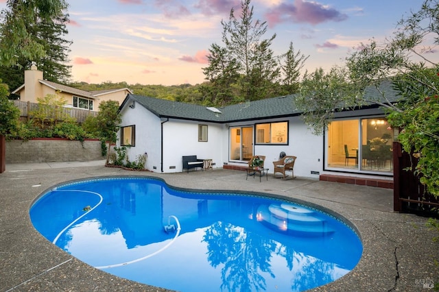 pool at dusk with a patio area