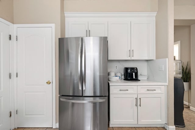 kitchen featuring white cabinets, light tile patterned floors, and stainless steel refrigerator