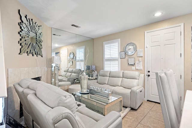 living room featuring a tile fireplace and light tile patterned flooring