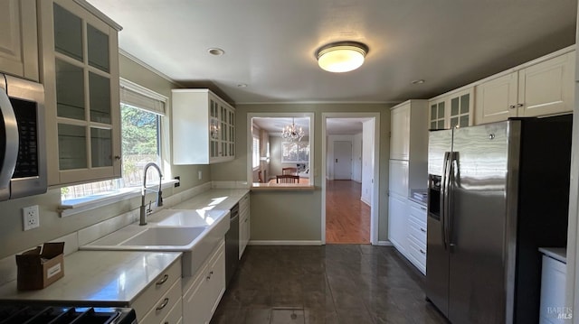 kitchen with white cabinetry, sink, appliances with stainless steel finishes, an inviting chandelier, and dark hardwood / wood-style flooring