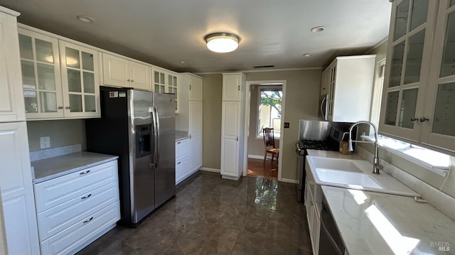 kitchen with stainless steel appliances, sink, crown molding, light stone countertops, and white cabinetry