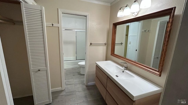 full bathroom featuring combined bath / shower with glass door, vanity, toilet, and ornamental molding