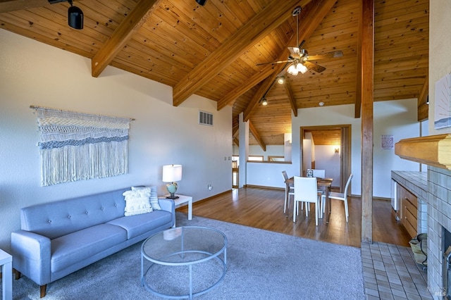 unfurnished living room with high vaulted ceiling, light hardwood / wood-style flooring, beamed ceiling, wood ceiling, and a tiled fireplace