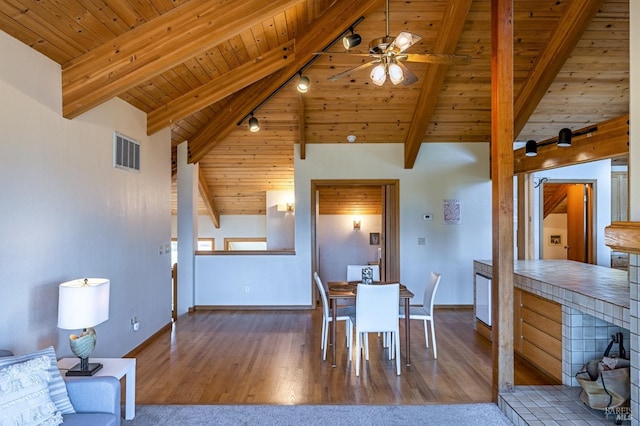 living room with wooden ceiling, dark wood-type flooring, a brick fireplace, ceiling fan, and beam ceiling