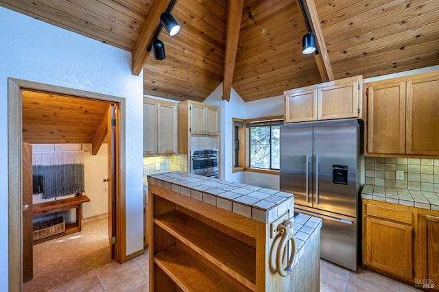 kitchen with stainless steel double oven, tasteful backsplash, vaulted ceiling with beams, tile countertops, and wood ceiling