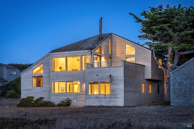 back house at dusk featuring a balcony